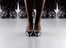 A person wearing high heels stands in front of a group of people wearing formal shoes, representing concepts like leadership or individuality.